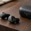 AURORAのロゴが入った黒色のワイヤレスイヤホンと充電ケース。