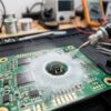 ロジンペンを使用して電子回路基板の部品に白い粉末を吹き付けている様子。